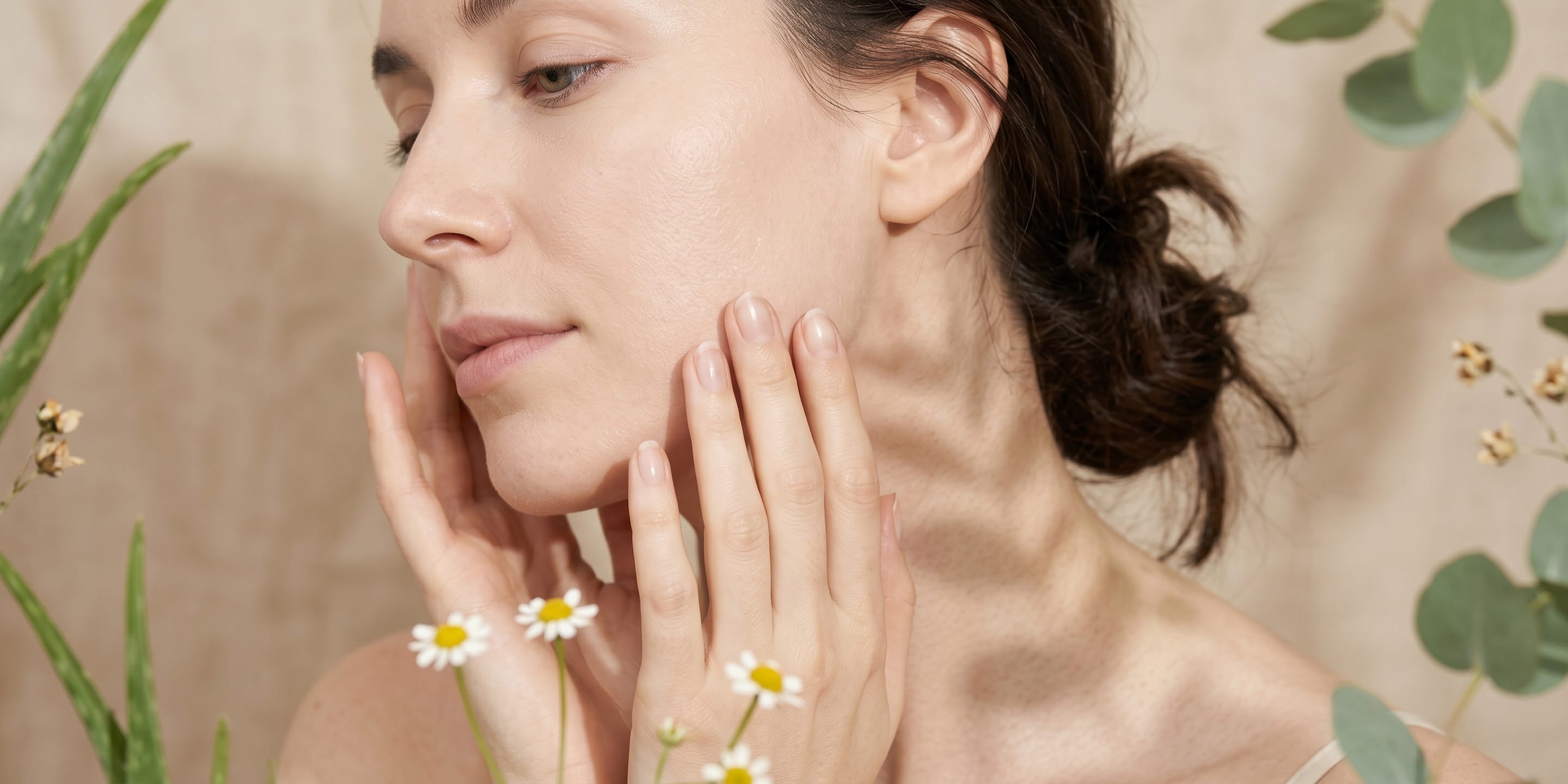 Woman touching her face with a natural background of plants and flowers.