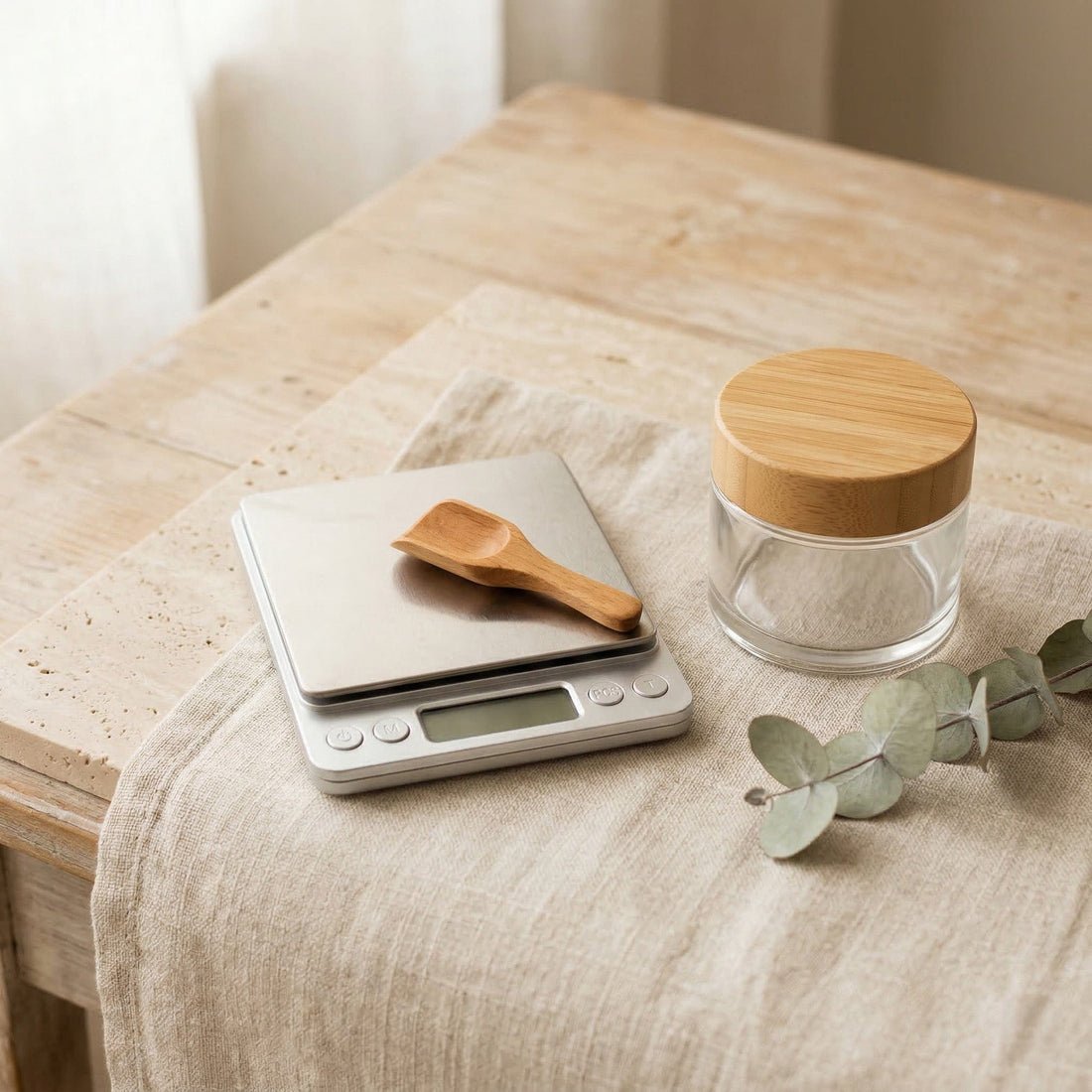 Digital precision scale with wooden spoon and glass jar on a wooden table.