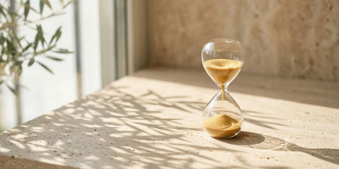 Hourglass with sand on a wooden surface with sunlight casting shadows.